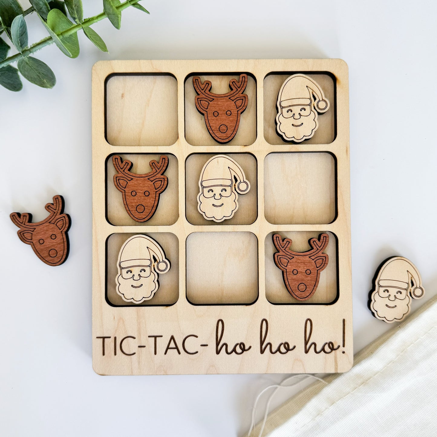 a wooden tictac - ho hoo game with santa and reindeer faces