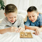 two boys laying on a bed playing with a wooden puzzle