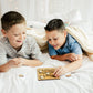 two boys laying on a bed playing with a board game