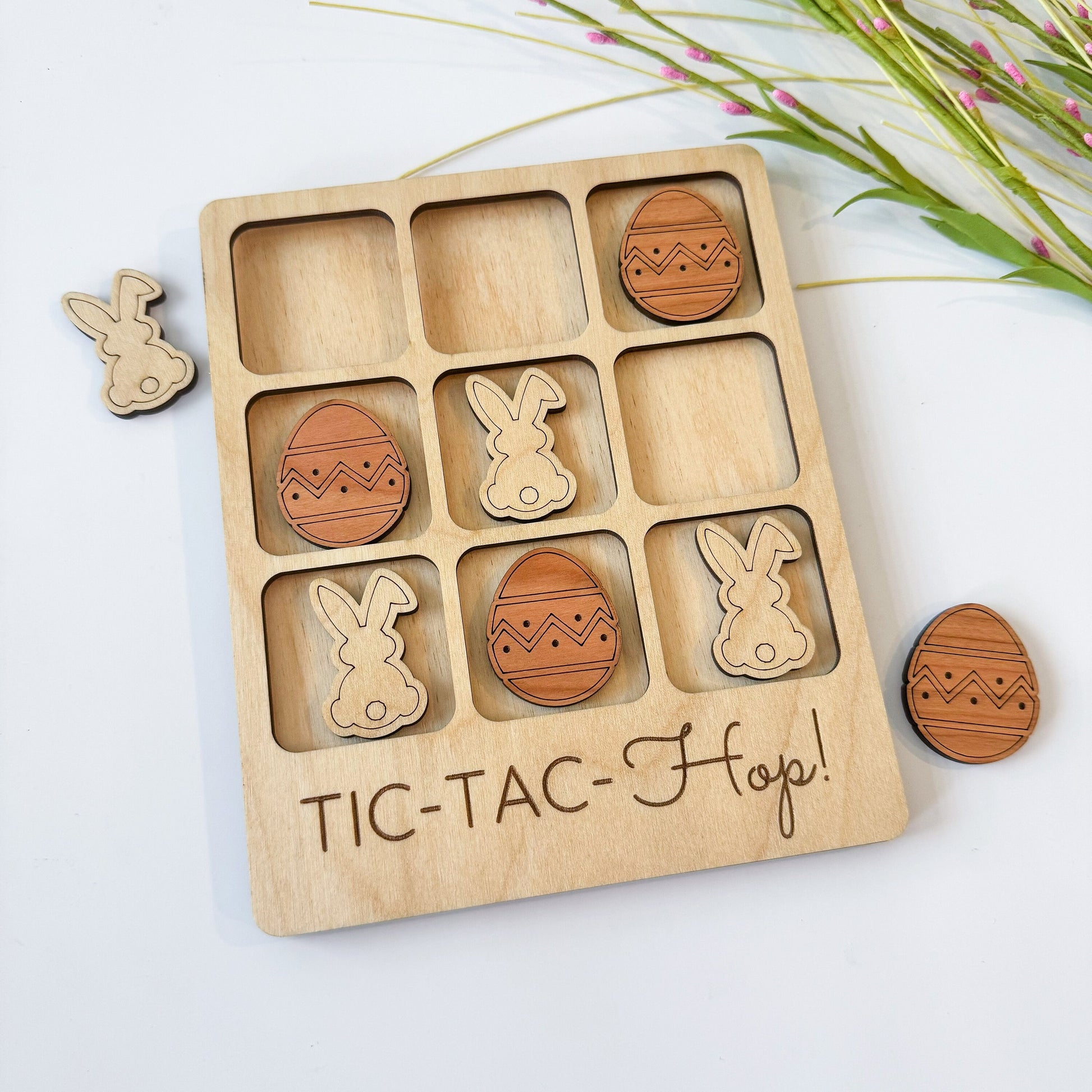 a wooden tic - tac - toe board with wooden easter eggs and bunny