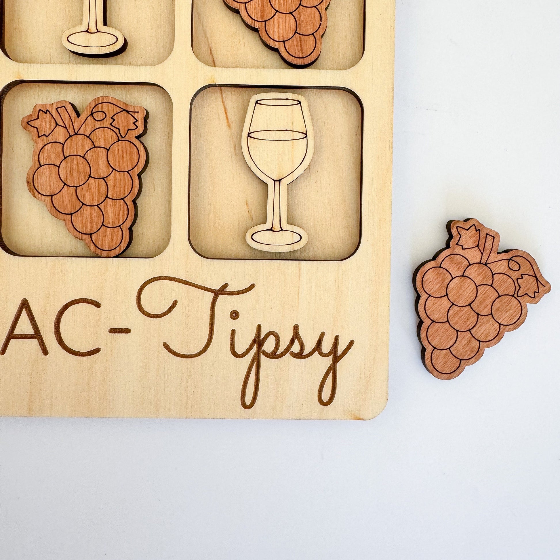 a wooden puzzle with a wine glass and grapes