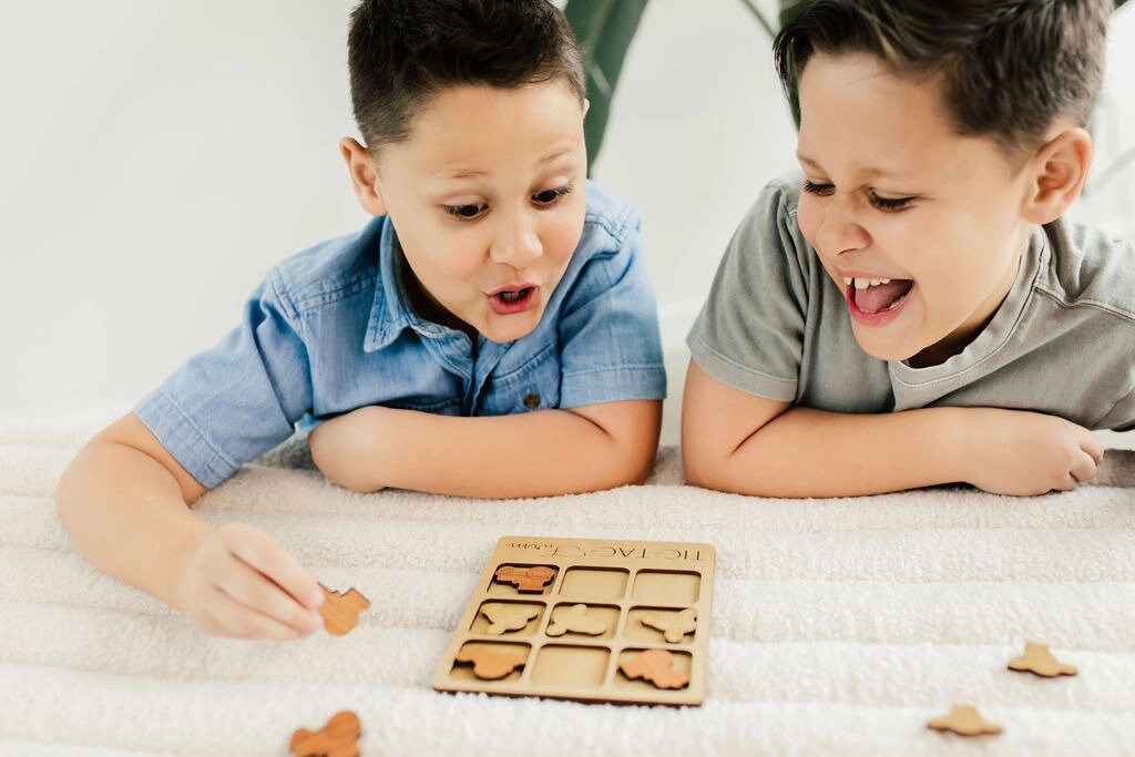 two young boys playing with a wooden puzzle