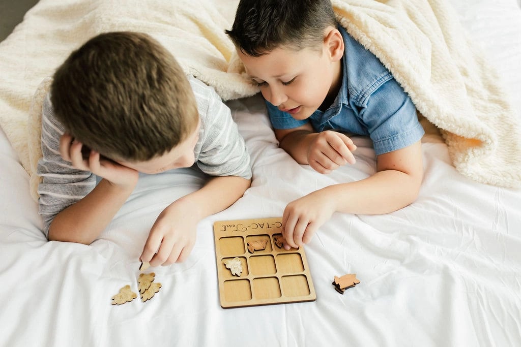 a boy and a boy laying in bed playing with a game