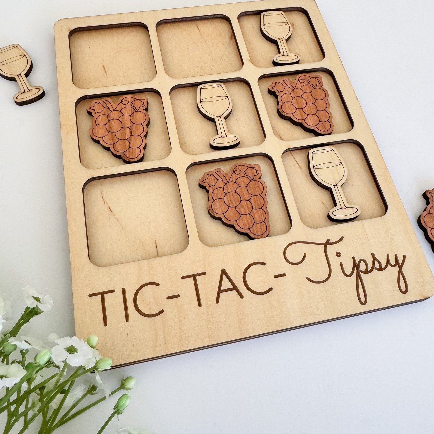 a wooden tictac - tipy tray with wine glasses and grapes