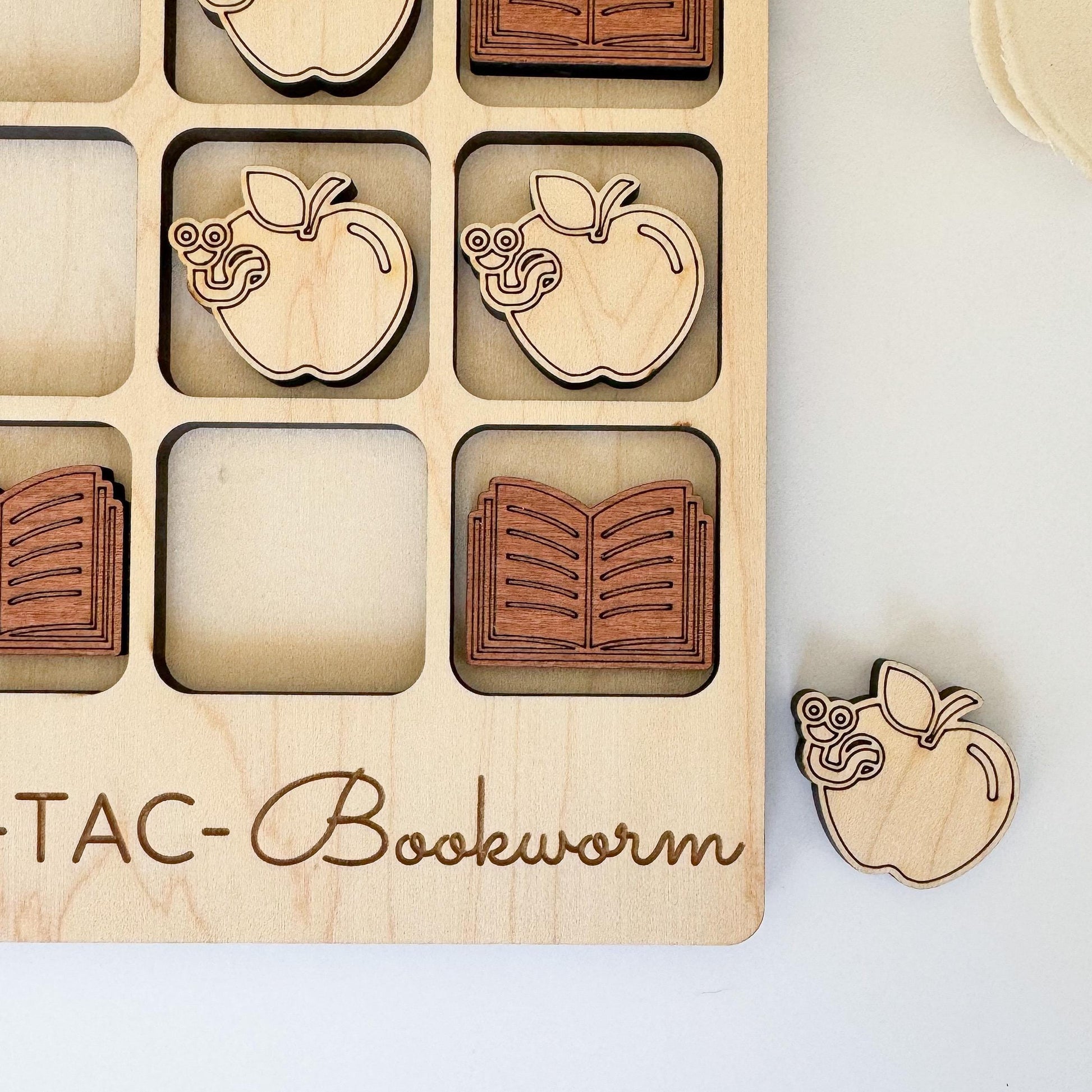 a wooden puzzle with a book and apple cutouts